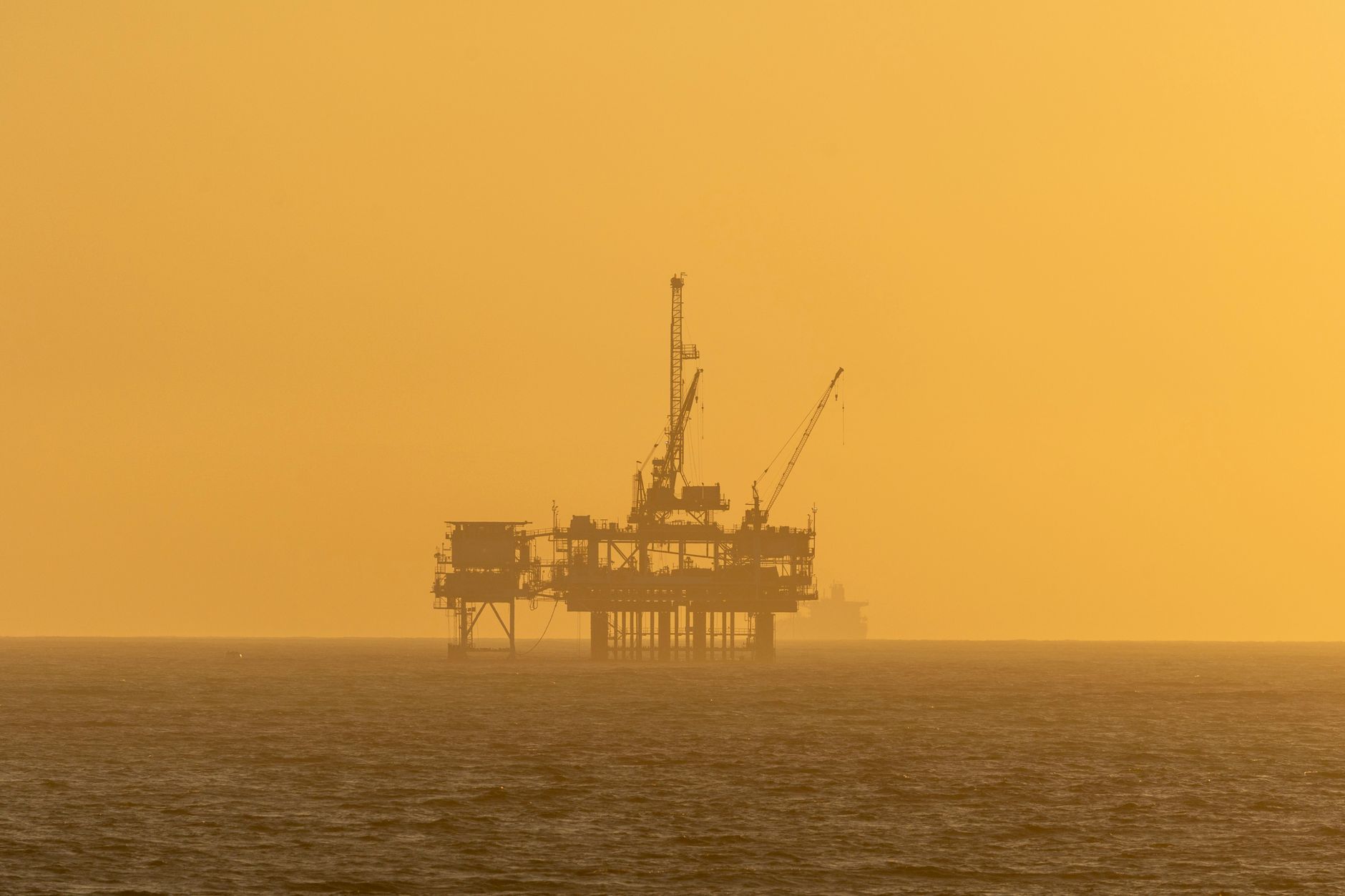 silhouette of offshore oil rig at sunset